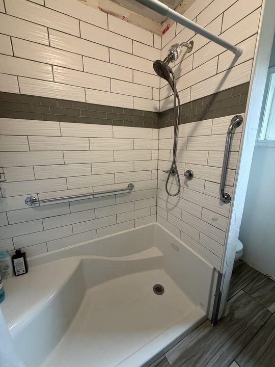 After: white subway tile shower with two chrome grab bars