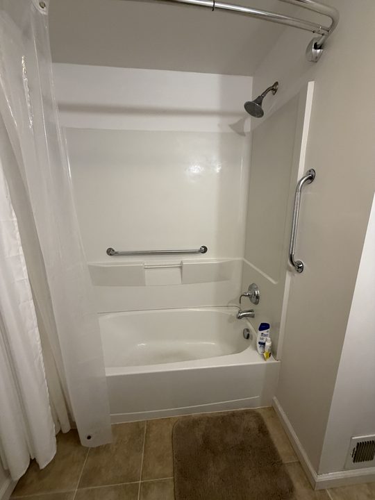 After: white tub surround with a horizontal and a vertical grab bar