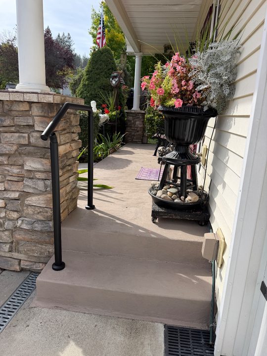 After: black handrail beside a two-step porch entry next to a stone column